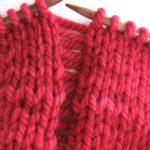 red knitting with a dropped knit stitch far down