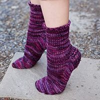 Purple toe-up socks with heel flap, shown from the side, on tip-toe