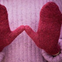 Red magic loop mittens with hands held palm out showing thumb