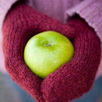 Red worsted-weight magic loop mittens with hands holding a green apple