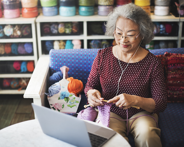 Woman sitting at computer in yarn shop knitting