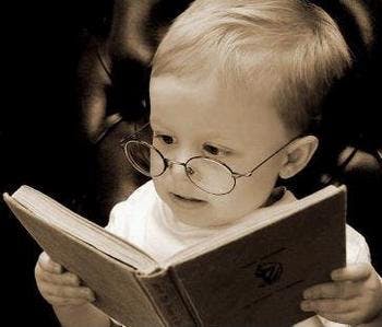baby with glasses reading a book